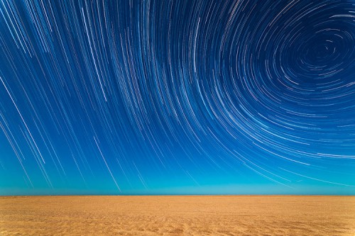 Multiple shots are compiled to create a time-lapse effect, as the Earth’s rotation draws the light from the stars into long trails arcing over the beach in Mar de Ajo, Buenos Aires Province, Argentina.